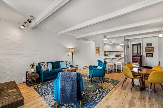 living room with beam ceiling, wood finished floors, brick wall, and a baseboard radiator