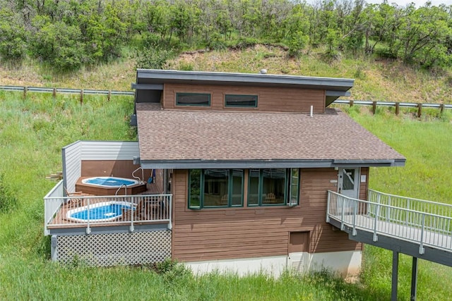 view of front of property with roof with shingles, a deck, and fence