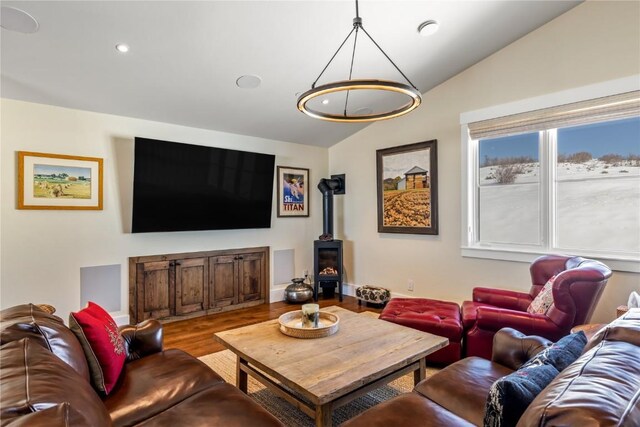 living room featuring hardwood / wood-style flooring, vaulted ceiling, and a wood stove