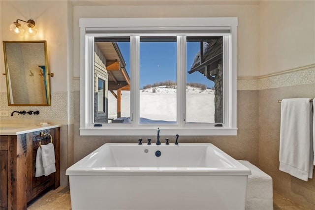 bathroom with vanity, a bathtub, and tile walls