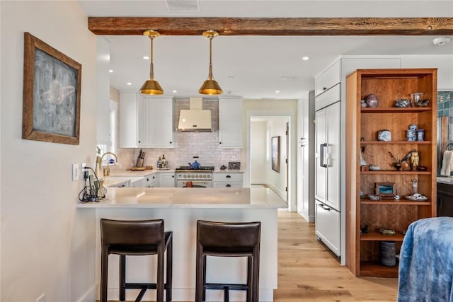 kitchen featuring white cabinetry, hanging light fixtures, high end stainless steel range oven, kitchen peninsula, and wall chimney range hood