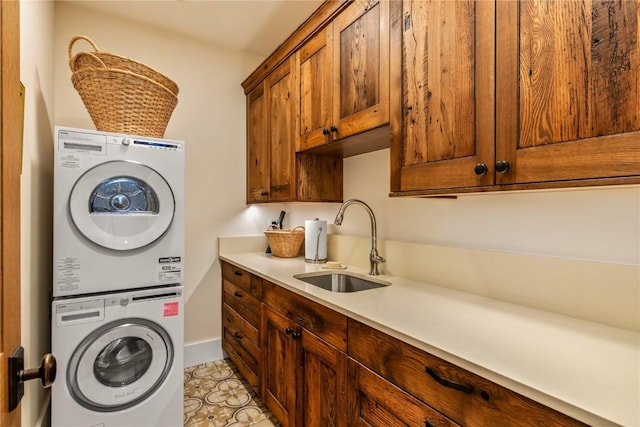 washroom featuring cabinets, stacked washer and clothes dryer, and sink