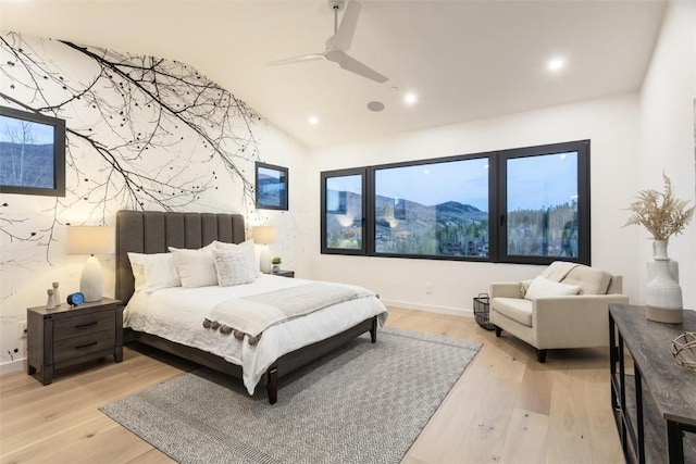 bedroom featuring a mountain view, light wood-type flooring, vaulted ceiling, and ceiling fan