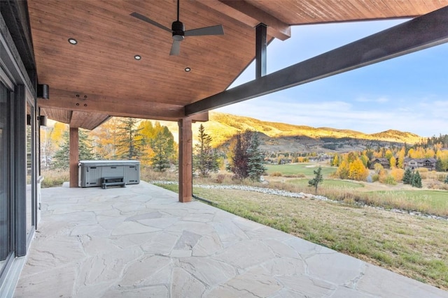 view of patio / terrace featuring ceiling fan, a mountain view, and a hot tub