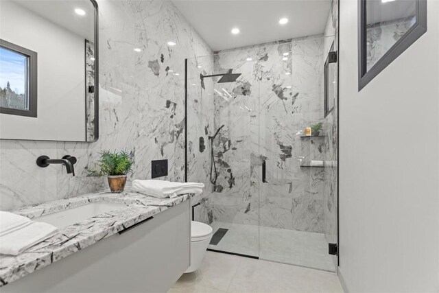 bathroom featuring vanity, toilet, walk in shower, and tile walls