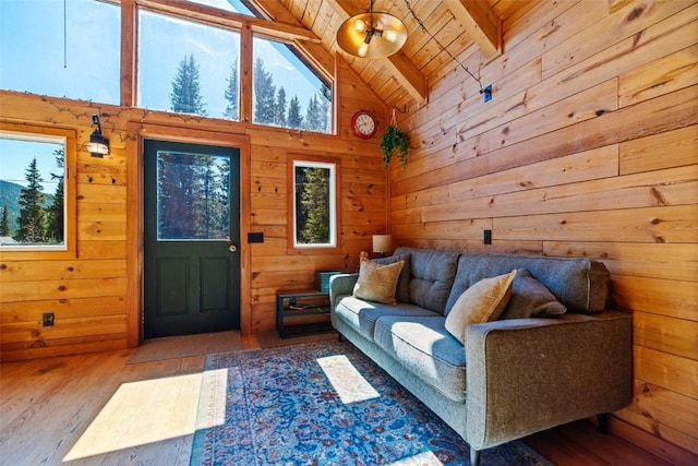 living room featuring wood walls, high vaulted ceiling, light wood-type flooring, beamed ceiling, and wood ceiling