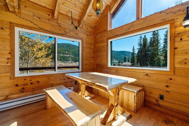 unfurnished dining area with a mountain view, wooden ceiling, vaulted ceiling with beams, a baseboard radiator, and light hardwood / wood-style floors