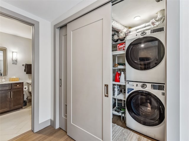 washroom with light hardwood / wood-style flooring and stacked washer and dryer