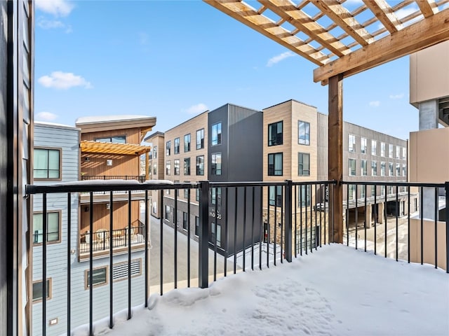 snow covered back of property with a pergola