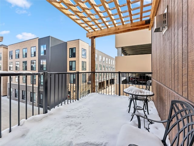 snow covered back of property with a pergola