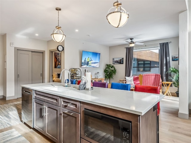 kitchen with ceiling fan, a kitchen island with sink, black microwave, dishwasher, and sink