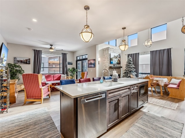 kitchen with ceiling fan, a kitchen island with sink, dishwasher, built in microwave, and hanging light fixtures