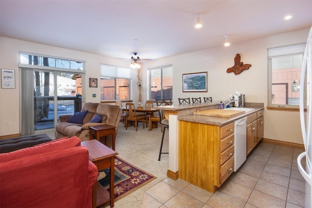 kitchen featuring kitchen peninsula, a breakfast bar, ceiling fan, light tile patterned floors, and dishwasher