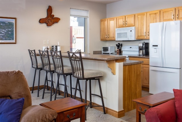 kitchen with a toaster, a peninsula, white appliances, open floor plan, and a kitchen bar