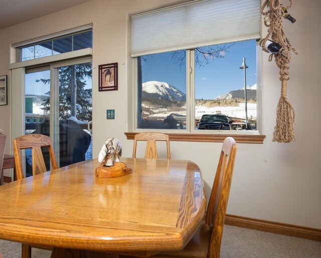 view of snow covered exterior with board and batten siding, a mountain view, and community garages