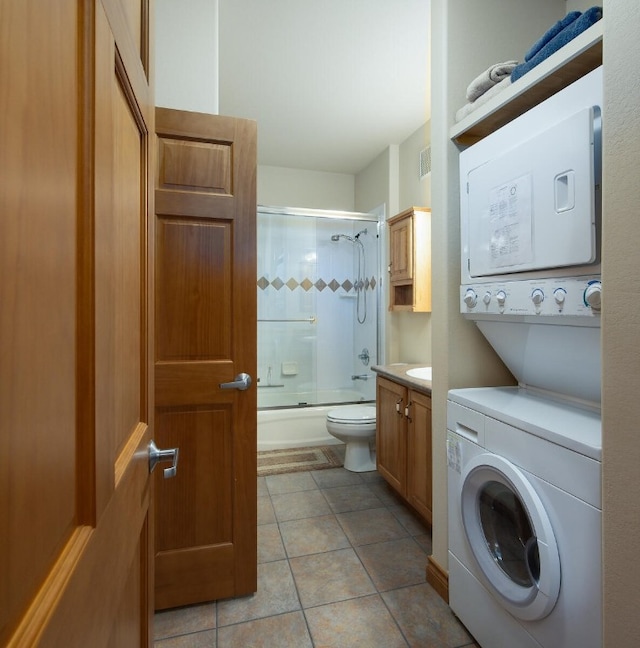 full bathroom with shower / bath combination with glass door, vanity, stacked washing maching and dryer, and toilet