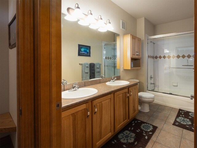 full bathroom with shower / bath combination with glass door, tile patterned flooring, vanity, and toilet