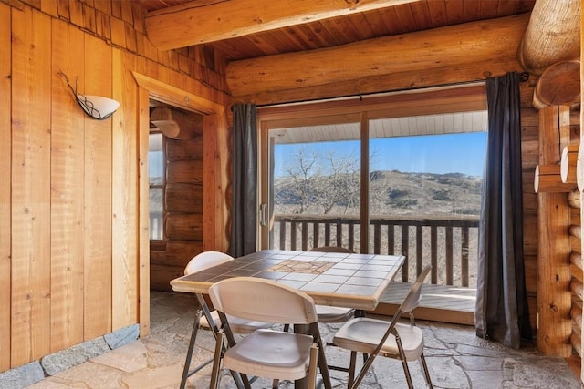 dining room featuring wood walls, wood ceiling, a mountain view, and beam ceiling