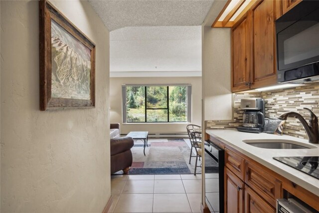 kitchen with sink, backsplash, a textured ceiling, light tile patterned floors, and black appliances