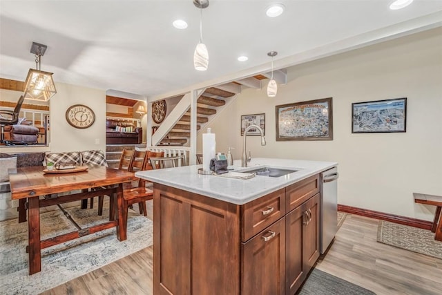 kitchen featuring dishwasher, decorative light fixtures, a kitchen island with sink, and sink