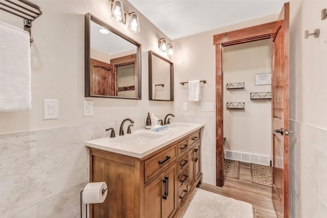 bathroom featuring wood-type flooring, vanity, and tile walls