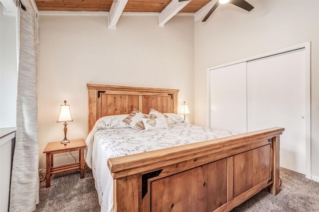 carpeted bedroom with lofted ceiling with beams, a closet, ceiling fan, and wooden ceiling