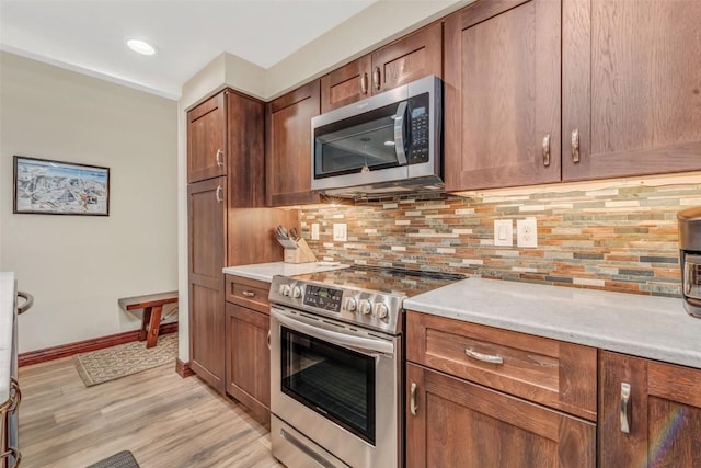 kitchen featuring decorative backsplash, light hardwood / wood-style flooring, and appliances with stainless steel finishes