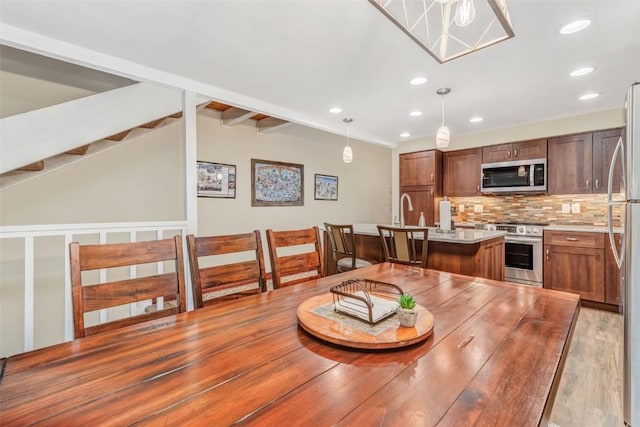 dining room featuring beamed ceiling and light hardwood / wood-style floors