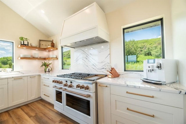 44255 Diamondback Way, Steamboat Springs, CO 80487 - kitchen with range with two ovens, custom exhaust hood, light stone countertops, backsplash, and light wood-type flooring