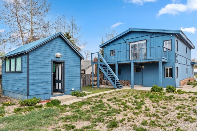 back of house with stairway, an outdoor structure, and fence