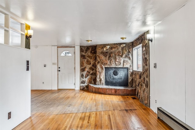 unfurnished living room with a baseboard heating unit and hardwood / wood-style floors