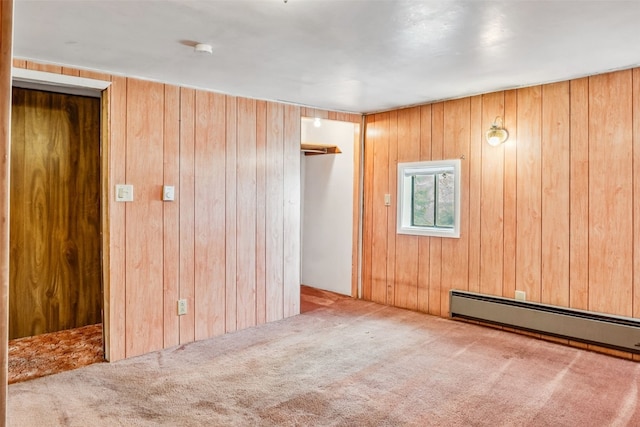 empty room with a baseboard heating unit, wooden walls, and carpet