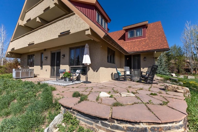 40924 Purple Sage St, Steamboat Springs, CO 80487 - back of property featuring a patio, stucco siding, and roof with shingles