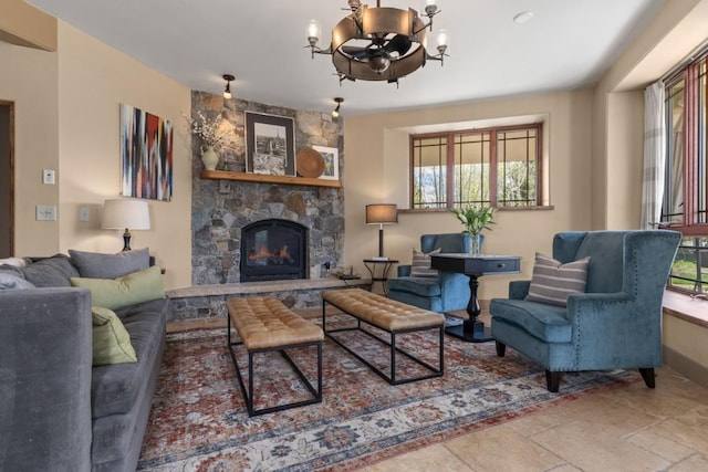 40924 Purple Sage St, Steamboat Springs, CO 80487 - living room featuring a chandelier, a stone fireplace, stone tile flooring, and baseboards
