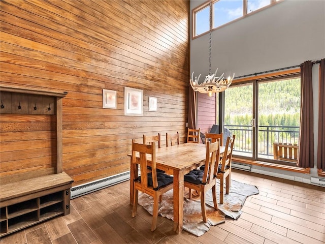 22320 US Highway 6 Unit 1761, Keystone, CO 80435 - dining area featuring a chandelier, a baseboard heating unit, wooden walls, a towering ceiling, and wood finished floors