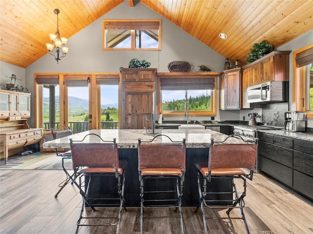 89 Emerald Rd, Silverthorne, CO 80498 - kitchen with stainless steel microwave, high vaulted ceiling, light stone countertops, a chandelier, and decorative light fixtures