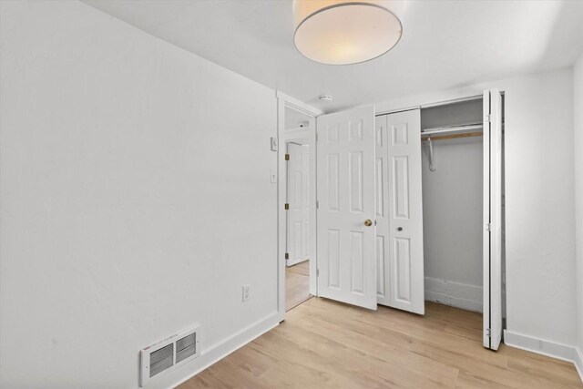 unfurnished bedroom featuring light hardwood / wood-style floors and a closet