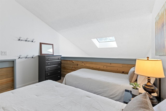 bedroom featuring a textured ceiling and vaulted ceiling with skylight