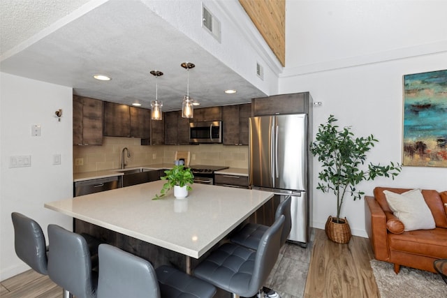 kitchen featuring dark brown cabinets, baseboards, a sink, and appliances with stainless steel finishes