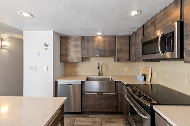 kitchen with stainless steel appliances, a textured ceiling, dark brown cabinets, decorative backsplash, and light countertops
