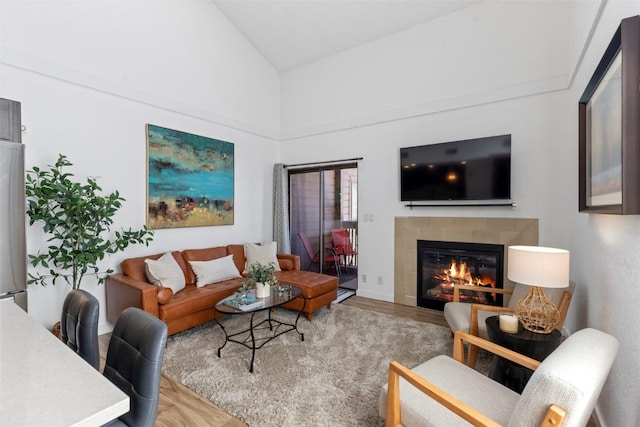 living area featuring a tile fireplace, wood finished floors, and high vaulted ceiling