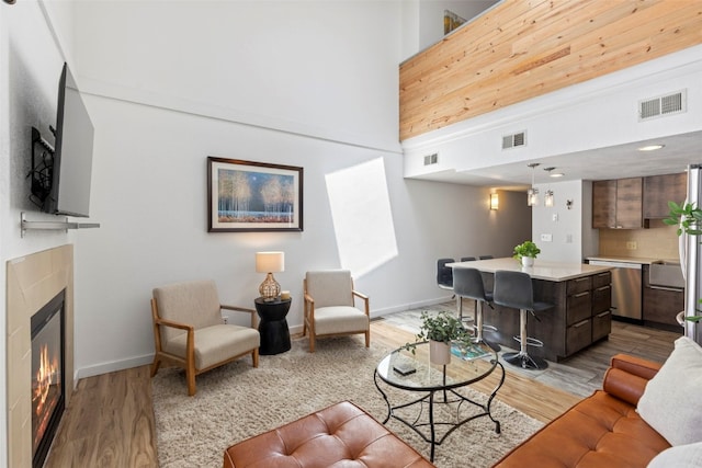 living area with a towering ceiling, visible vents, and light wood-style flooring