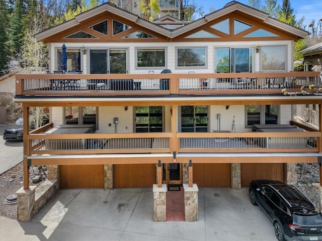 2137 Overlook Ln Unit 104, Steamboat Springs, CO 80487 - back of house featuring a balcony, concrete driveway, and stone siding