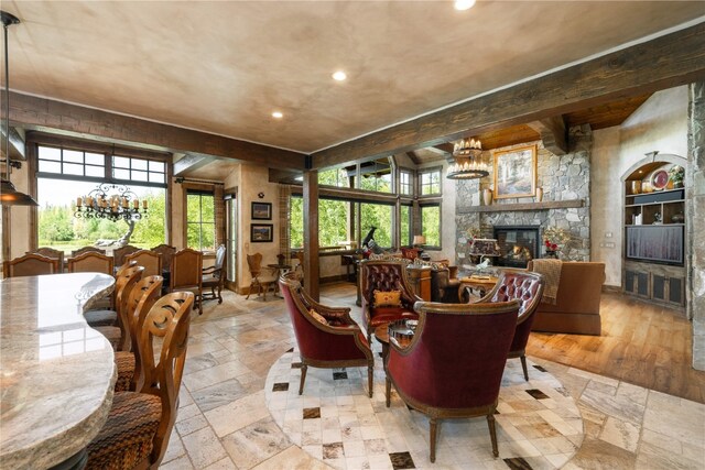 interior space with stone tile floors, a fireplace, a chandelier, and beamed ceiling