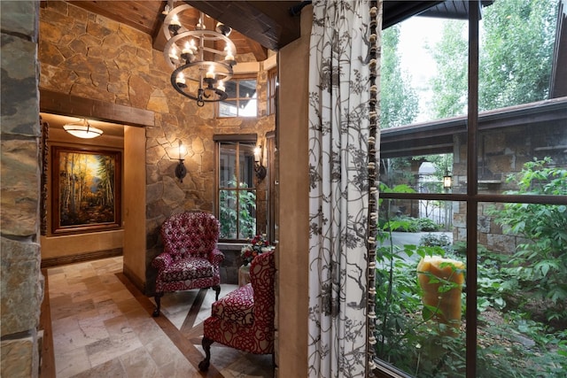 interior space featuring stone tile flooring, beamed ceiling, and an inviting chandelier