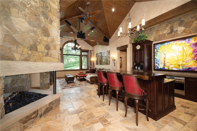 bar with stone tile floors, wood ceiling, oven, a stone fireplace, and high vaulted ceiling