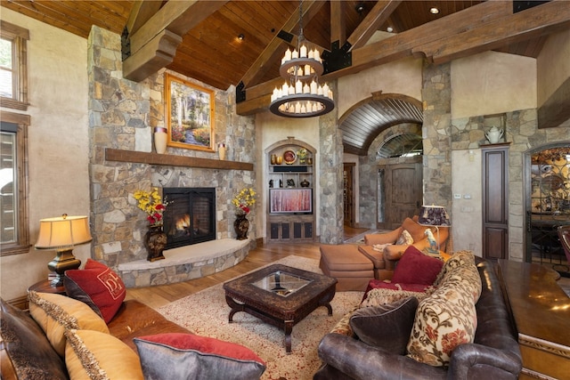 living area with beam ceiling, a stone fireplace, wood finished floors, high vaulted ceiling, and wooden ceiling