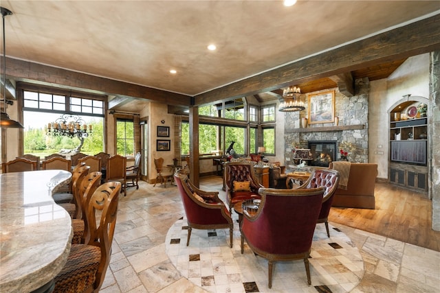 interior space featuring a chandelier, a fireplace, beamed ceiling, and stone tile floors