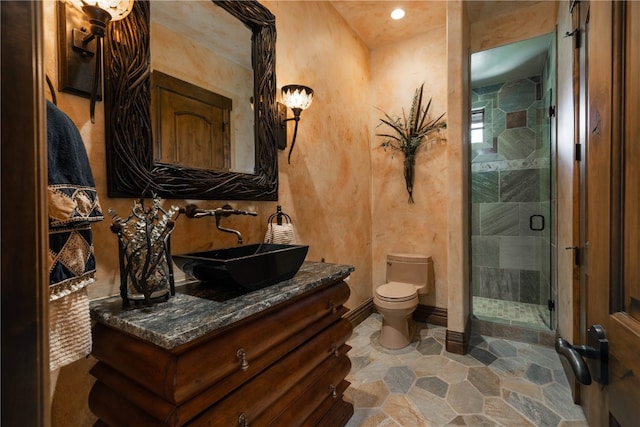 full bathroom with toilet, a stall shower, stone finish flooring, vanity, and baseboards