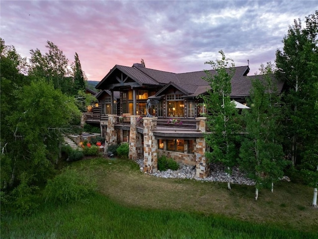 rear view of property featuring stone siding, a yard, a chimney, and stairs